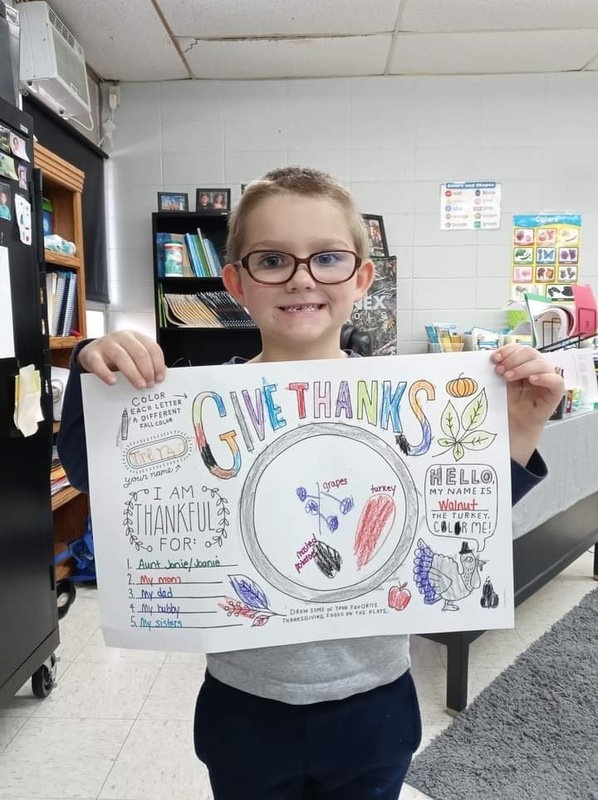 Child holding a Give Thanks poster
